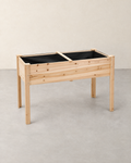 Empty natural fir wood raised garden bed on four legs with a black fabric liner