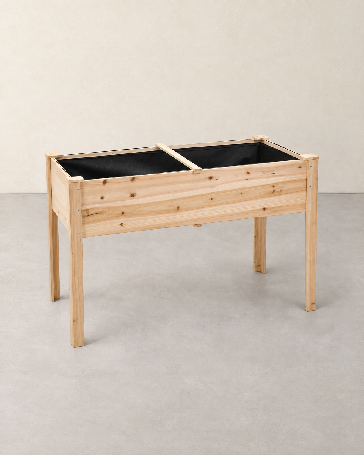 Empty natural fir wood raised garden bed on four legs with a black fabric liner
