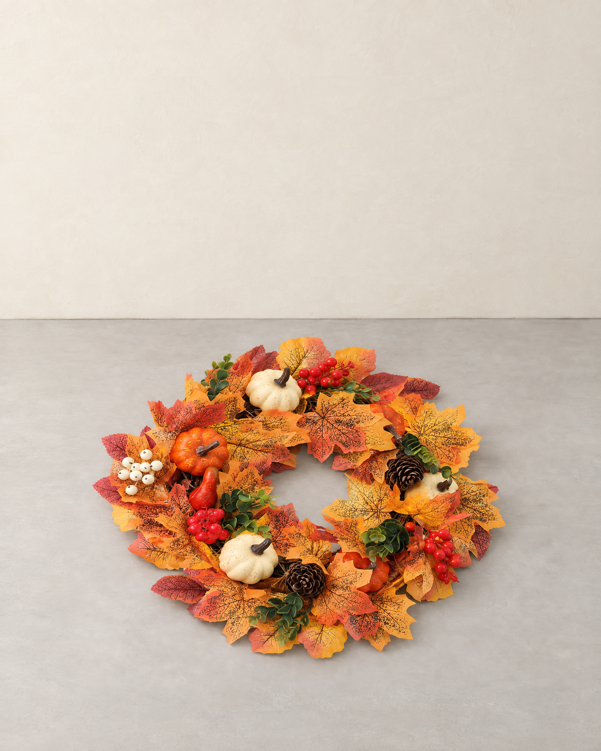 Autumn wreath with white and orange pumpkins, maple leaves, red berries and pine cones, lying flat