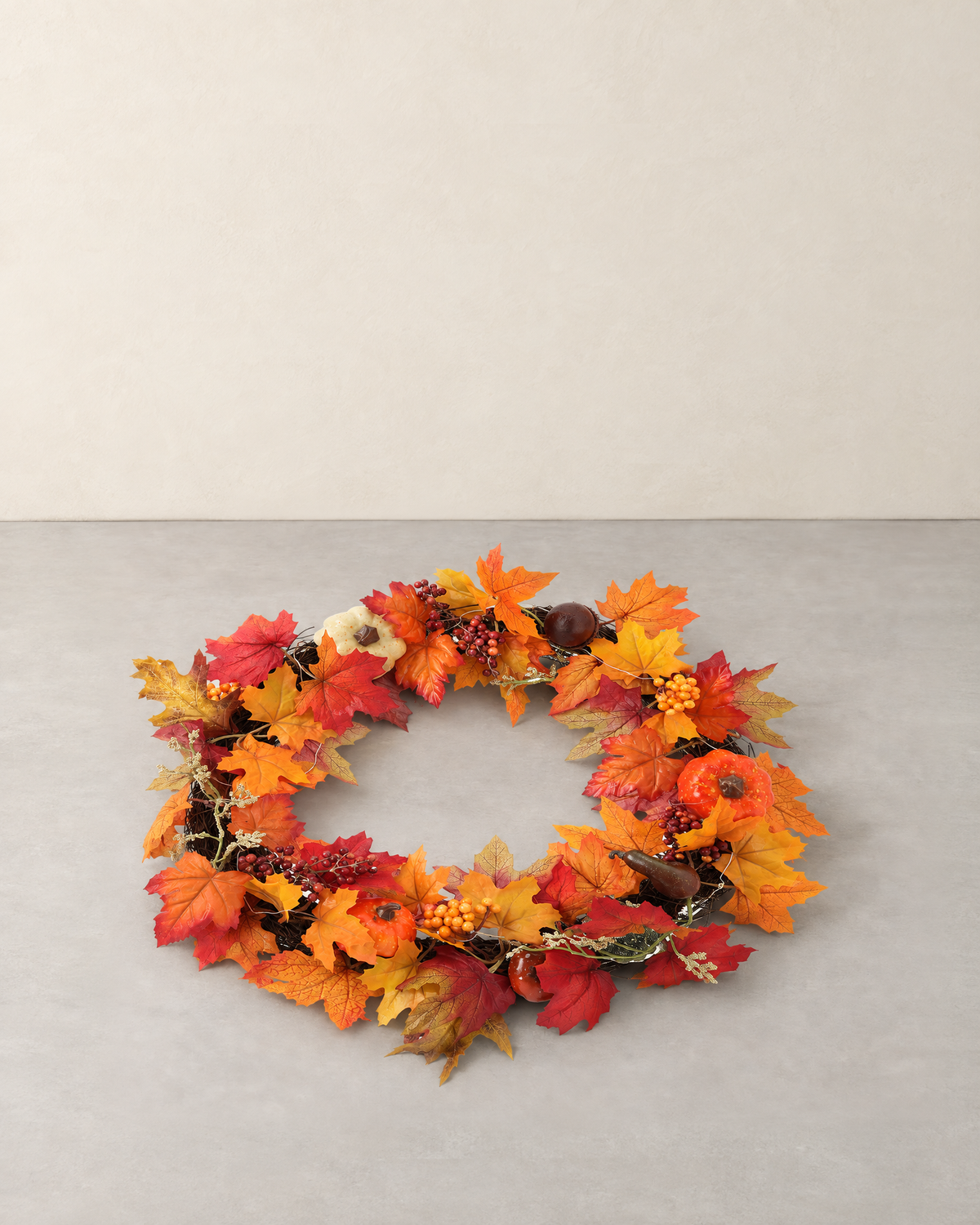 Autumn wreath of maple leaves, berries and small pumpkins on a woven branch ring, lying flat