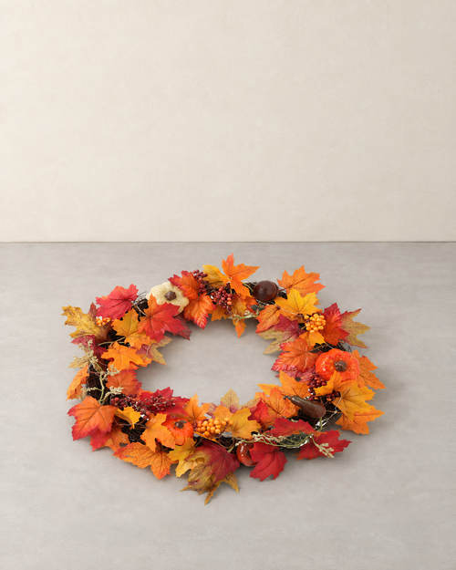 Autumn wreath of maple leaves, berries and small pumpkins on a woven branch ring, lying flat