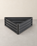 Empty triangular dark grey corrugated steel raised garden bed with bolted corner posts