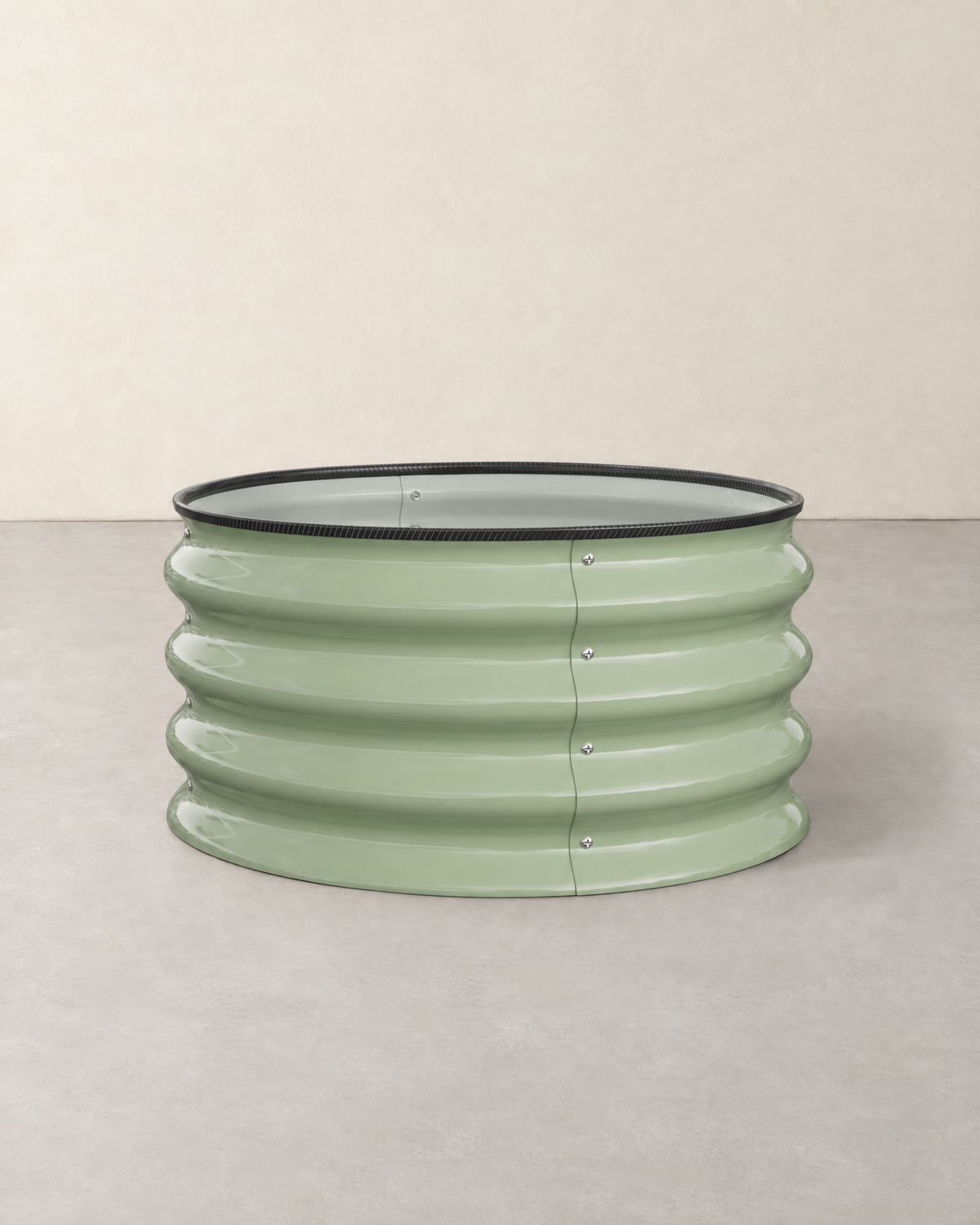 Round sage green corrugated steel raised garden bed with a black rubber rim, empty