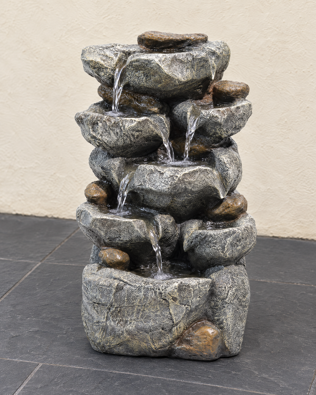 Water running down the stacked rock ledges of the cascade fountain on slate paving