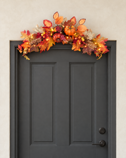 The autumn swag with its lights on, hung across the top of a charcoal front door