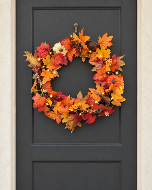 The branch ring autumn wreath with its lights on, hung on a charcoal front door
