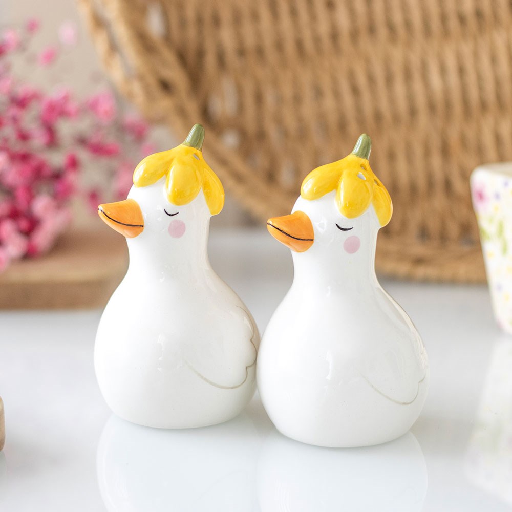 Duck shakers in yellow flower hats on a table in front of a wicker basket
