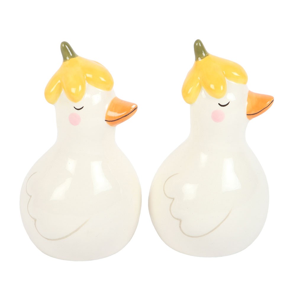 Close view of the two white ceramic ducks with yellow petal hats and pink cheeks on white